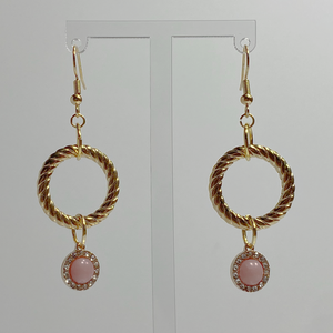 Gold-toned hanging earrings with a gold-plated hoop with a small with a hanging pink gem surrounded by white crystals.